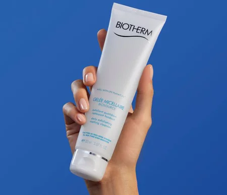Exfoliant Biotherm dans une main sur fond bleu