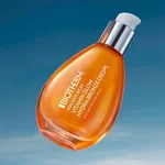 Flacon et pots de soin Biotherm Aquasource+ en verre orange, presentes sur fond orange vif, avec couvercles argentes et gel hydratant visible.
