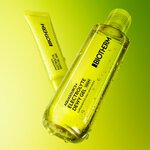 Flacon transparent et tube jaune Biotherm Aquasource+ Eau de Lait Demaquillante, avec gouttelettes d’eau visibles, sur fond vert degrade lumineux.