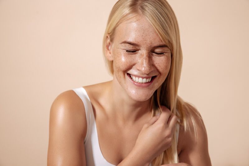  Woman is looking at the camera and holding her hand in front of her face to protect from the sun