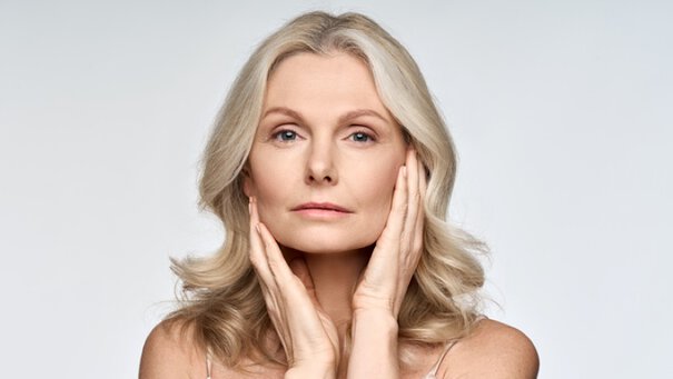 Woman against a blue background looking over her shoulder