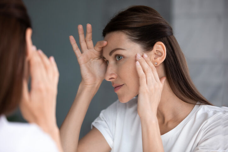 Woman examines her face in the mirror